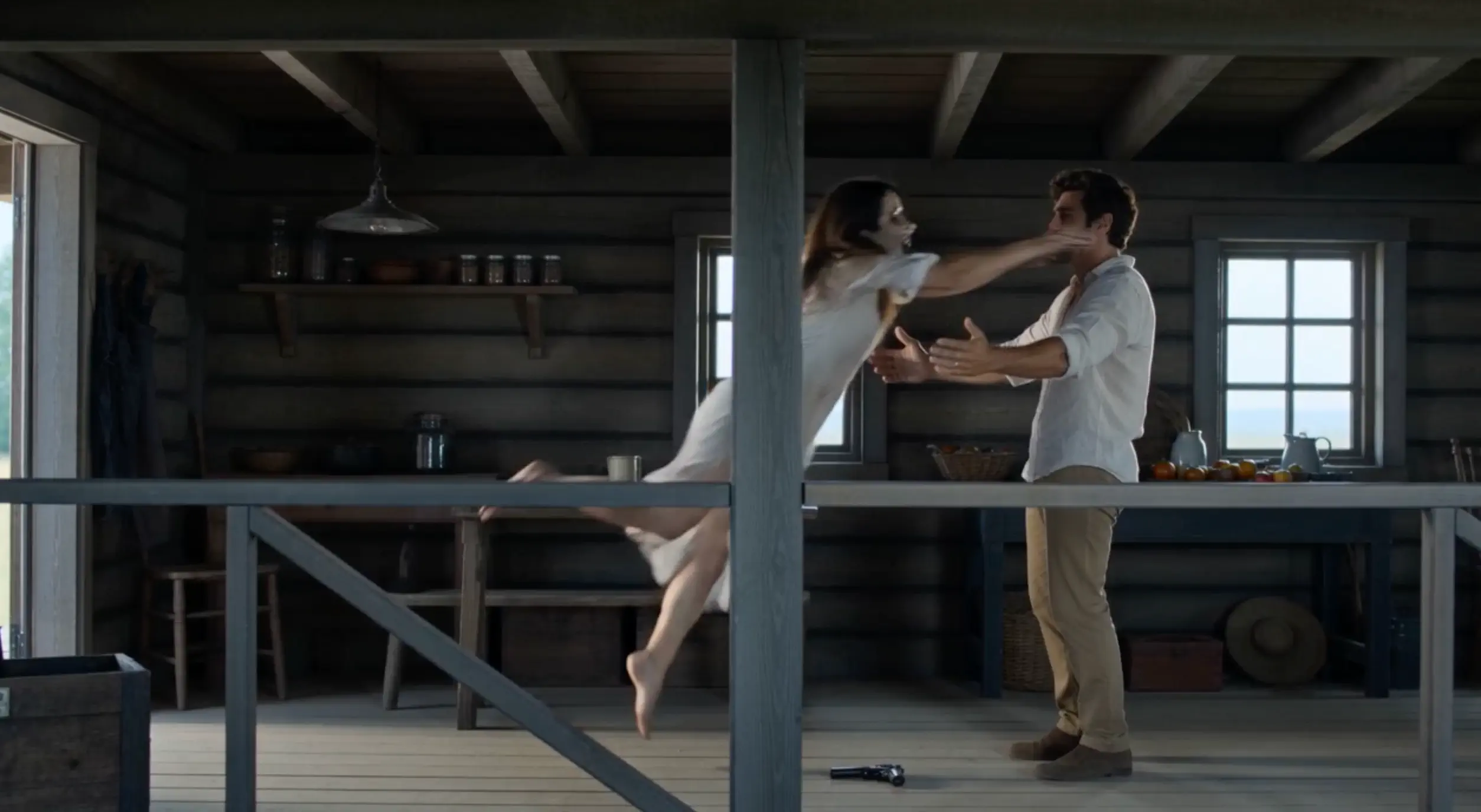 A side view of the zombie leaping toward the survivor’s open arms in the cabin